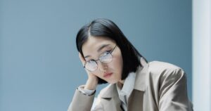 職場で頬杖をつき疲れた表情の女性