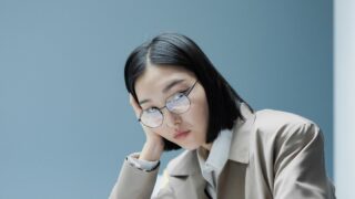 【判例紹介】執拗な退職勧奨で適応障害がうつ病に悪化、労災と認定|国・渋谷労基署長事件 1 職場で頬杖をつき疲れた表情の女性